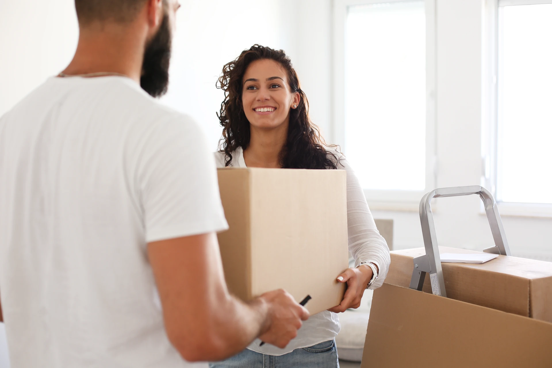 Photo of a couple carrying moving boxes.